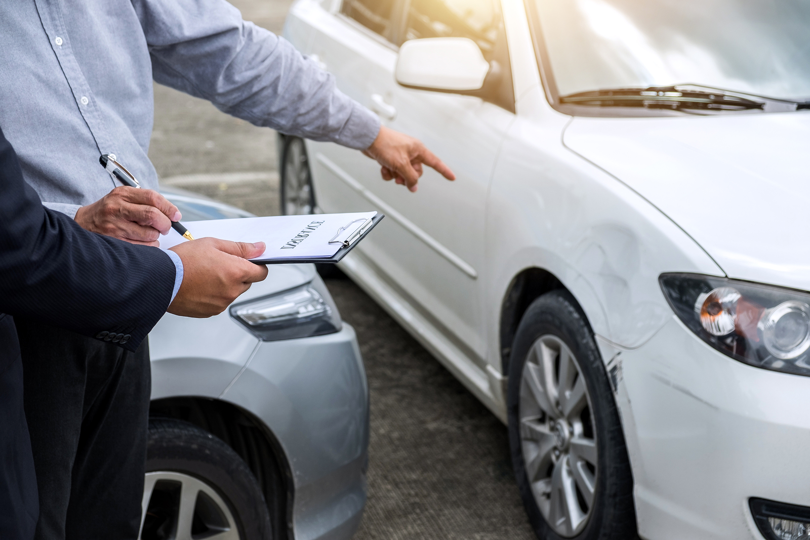 Insurance Agent examine Damaged Car and filing Report Claim Form after accident, Traffic Accident and insurance concept.